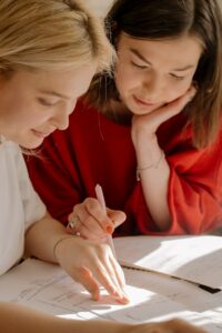 Woman in Red Shirt Holding Pen Writing on White Paper