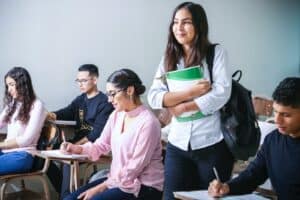 woman carrying white and green textbook, college students